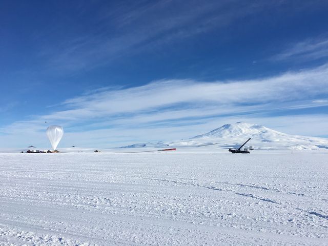 The image captures the launch of NASA's BACCUS mission from Antarctica's Ross Ice Shelf near McMurdo Station. The snowy landscape, clear blue sky, and distant mountains provide a stunning backdrop for the scientific endeavor. Perfect for articles and publications related to space research, atmospheric science, remote expeditions, and environmental studies. Can also be used for educational materials showcasing scientific missions and the extreme environments scientists work in.