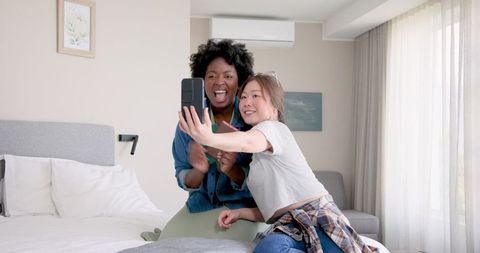 Joyful Lesbian Couple Packing for Vacation and Taking Selfie