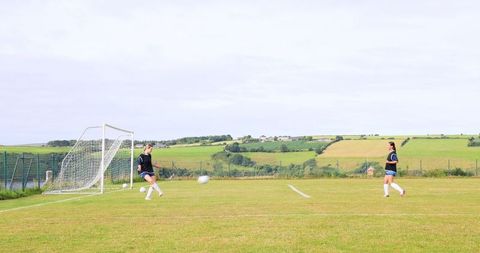 Teenage girls playing soccer on scenic rural field