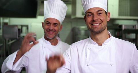 Cheerful Chefs Giving OK Gesture in Professional Kitchen