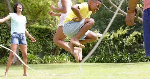 Family having fun skipping rope outdoors on sunny day
