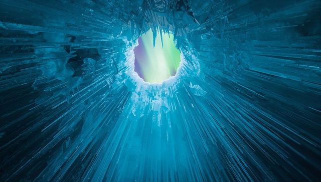 Surreal ice cave featuring aurora borealis