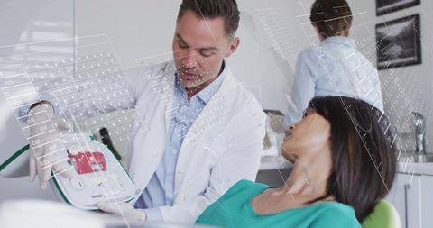 Dentist explaining handheld dental device to patient during chairside consultation
