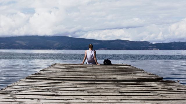 Solitary Woman Reflecting on Wooden Pier by Tranquil Lake - Download Free Stock Photos Pikwizard.com