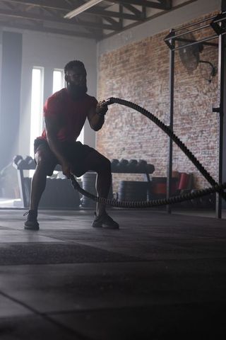 African american man performing intense battle-rope workout in gritty industrial gym