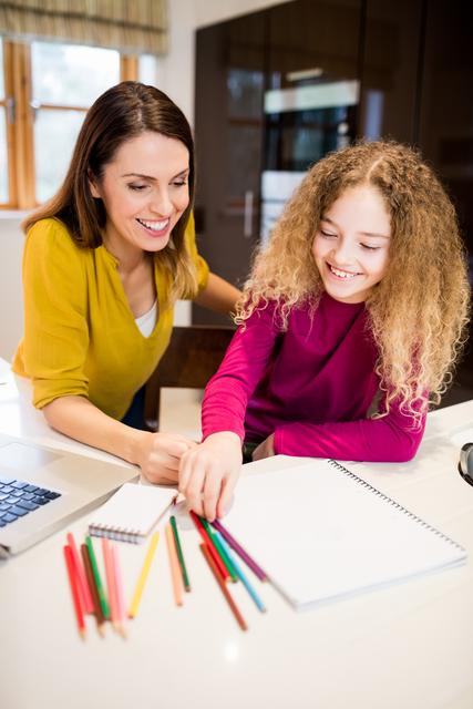 Mother and daughter helping daughter with her homework in kitchen