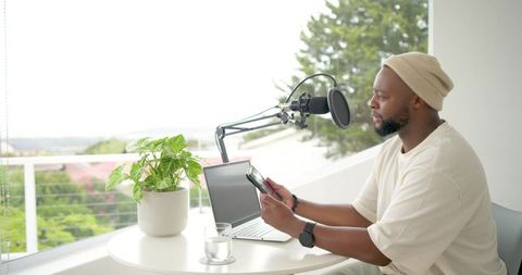 Recording podcast on balcony using boom microphone, laptop and smartphone in daylight