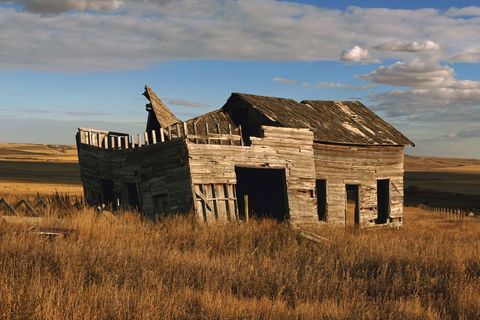 Abandoned Weathered Farmhouse in Rural Fields Under Blue Sky