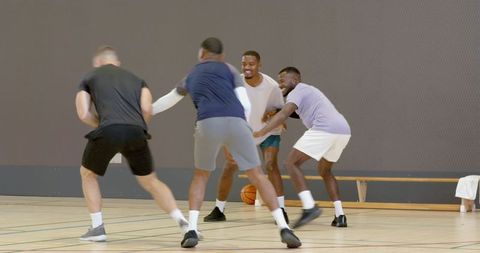 Men scrambling for loose basketball during friendly indoor pickup game