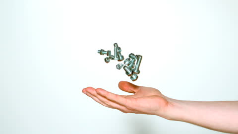 Hand Tossing Metallic Bolts and Screws Against White Background