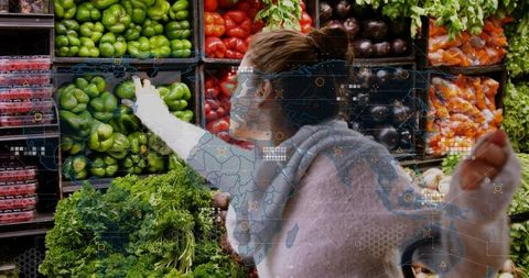 Reaching woman selecting green bell peppers with ar watch overlay in supermarket