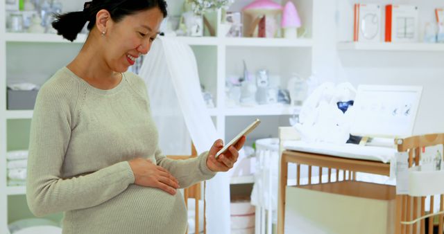 Pregnant Woman Smiling and Using Smartphone in Nursery Room - Download Free Stock Images Pikwizard.com