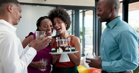 Colleagues celebrating farewell with woman blowing out candles