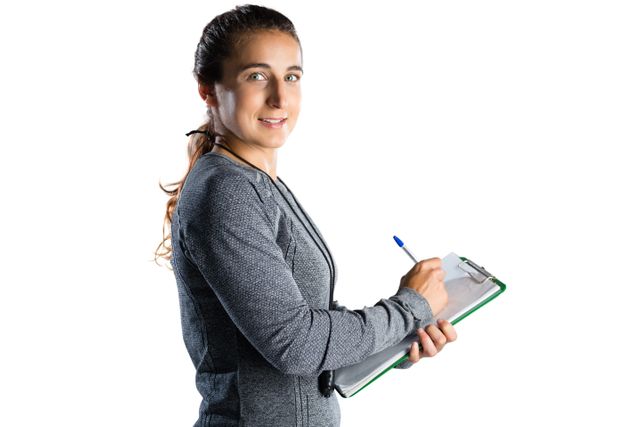 Female rugby coach writing on clipboard while standing against white background. Ideal for use in sports training materials, coaching guides, fitness programs, and sports management articles.