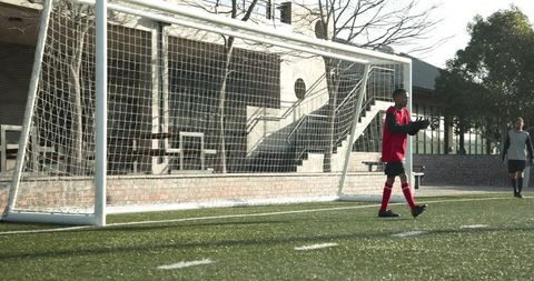Young Soccer Player Walking by Goalpost on Bright Day