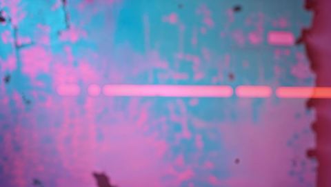 Glowing neon light on grungy wall with pink and blue hues