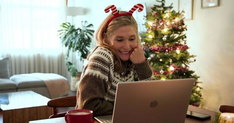 Middle Aged Woman Enjoying Christmas Season with Laptop in Cozy Home