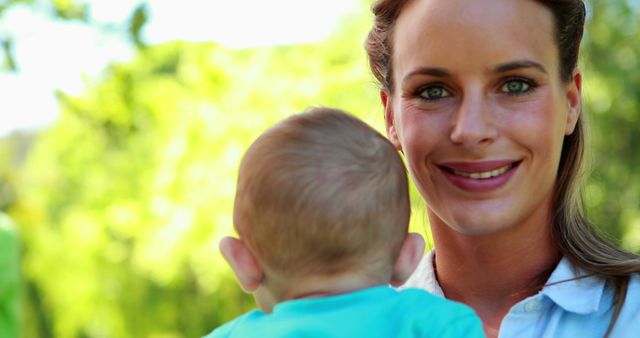 Smiling Mother Holding Baby In Sunny Park - Download Free Stock Images Pikwizard.com