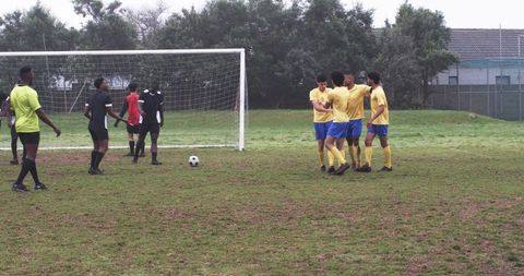 Teen soccer players celebrating goal on muddy field