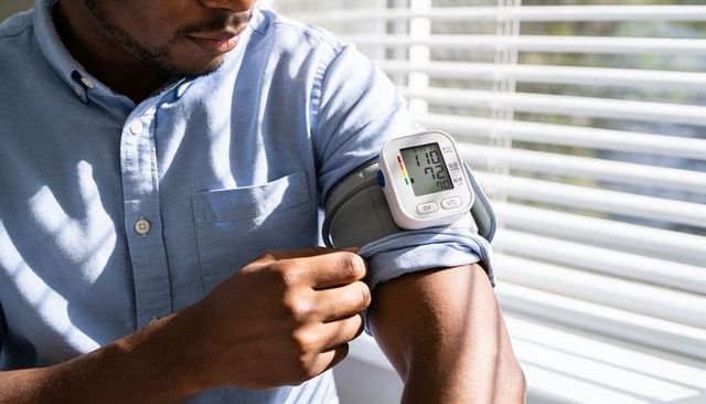 Man checking blood pressure at home using digital arm cuff for hypertension self-monitoring