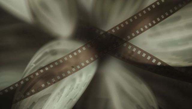 Backlit 35mm film strips showing sprocket holes, dust, scratches in abstract macro