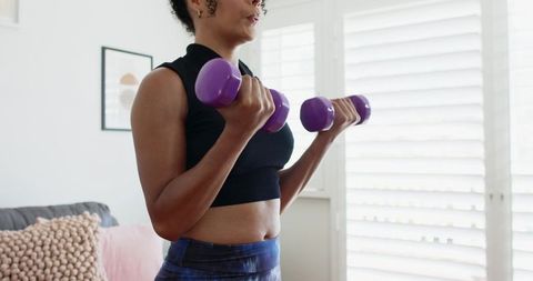 African American Woman Performing Home Bicep Curls with Purple Dumbbells