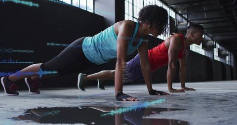 Couple holding plank on industrial warehouse floor with fitness waveform overlays