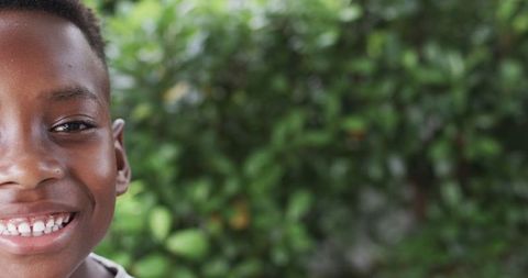 Joyful Young Boy Smiling in Lush Green Outdoor Scene