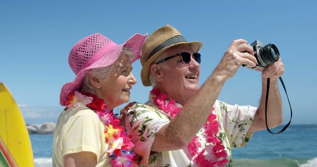 Senior couple enjoying beach vacation, wearing tropical outfits, taking selfie. Ideal for depicting happiness, leisure, travel, retirement lifestyle, and tourism advertisements.