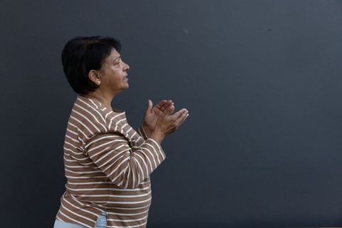 Elderly Woman Clapping in Striped Shirt Against Grey Background