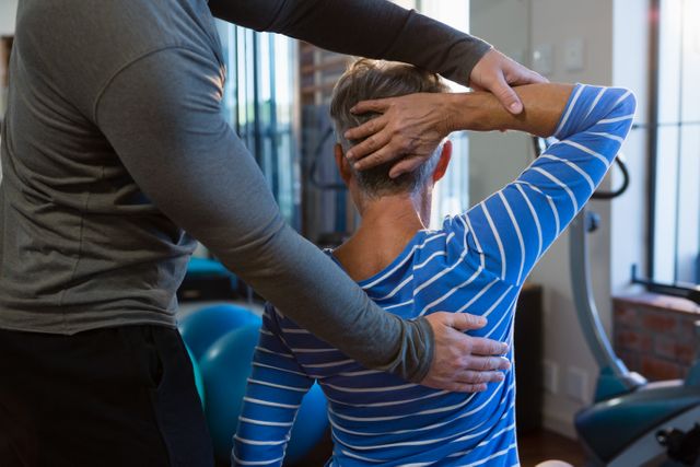 Senior woman receiving assistance from a physiotherapist during an exercise session at a clinic. Ideal for use in healthcare, rehabilitation, and wellness contexts, highlighting the importance of physical therapy and support for elderly patients.