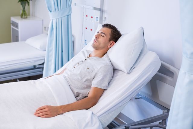 Male patient sleeping in hospital bed, ideal for illustrating healthcare, patient recovery, and medical treatment scenarios. Useful for medical articles, healthcare brochures, and hospital websites to depict patient care and hospital environments.