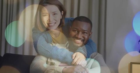 Chinese woman hugging partner on sofa smiling couple cozy bokeh living room warmth evening