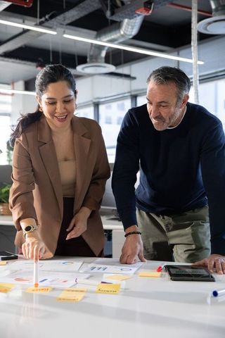 Diverse coworkers collaborating over charts and sticky notes on modern open-plan office table