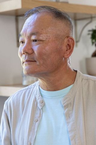 Senior asian man looking left wearing beige overshirt and light blue t-shirt indoor portrait