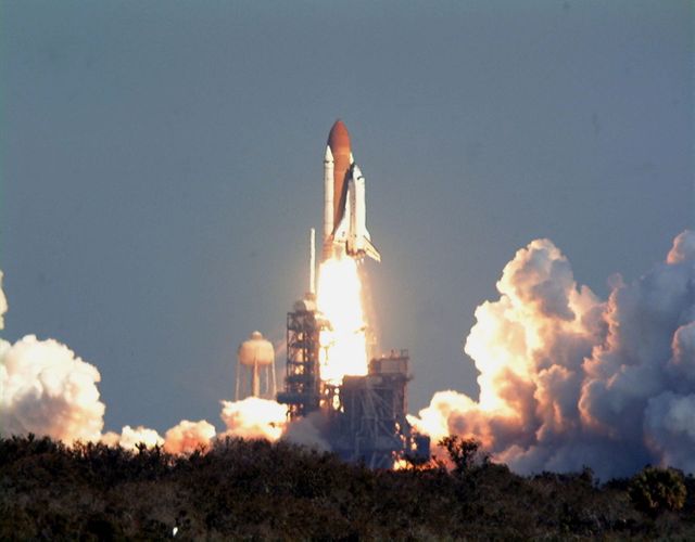 Image depicts moment of Space Shuttle Endeavour launch for mission STS-99 at Kennedy Space Center. Picture captures liftoff against a clear blue sky. Use for space exploration topics, NASA historic events, rocket launches.