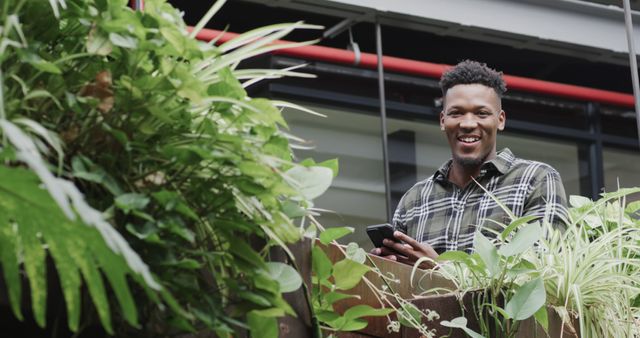 Smiling Young Male on Balcony Surrounded by Lush Plants - Download Free Stock Images Pikwizard.com