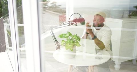 Content creator recording podcast at bright modern home office terrace with microphone
