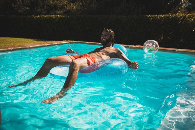 Caucasian man lying in inflatable toy chair in the pool sunbathing and relaxing. hanging out and relaxing outdoors in summer.