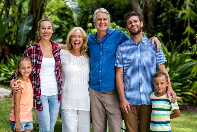This image shows a happy multigenerational family standing together in a lush garden. The family members are smiling and embracing each other, showcasing strong family bonds and joy. Ideal for use in advertisements, family-oriented content, and articles about family values, outdoor activities, and multigenerational living.