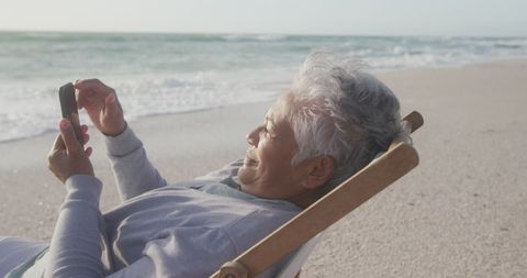 Senior Woman Relaxing on Beach with Smartphone at Sunset - Download Free Stock Images Pikwizard.com
