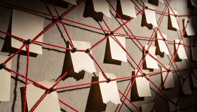 Red string conspiracy board with torn notes and black pins, dramatic investigation web