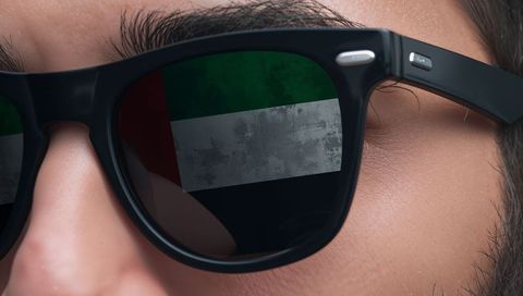 Close-up Man Wearing Black Wayfarer Sunglasses Reflecting UAE Flag, Stylish Urban Portrait