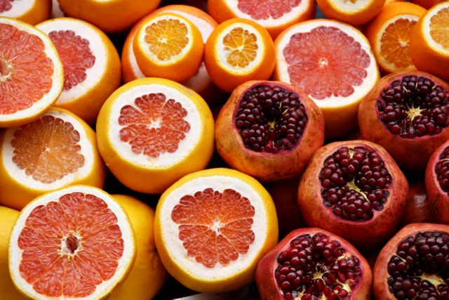 Colorful and vivid display of sliced citrus fruits and pomegranates showing vibrant interiors and juicy textures. Ideal for use in health and wellness blogs, nutrition articles, fresh produce marketing, or recipe designs.