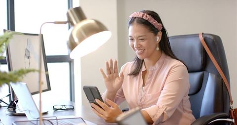 Businesswoman Connecting Remotely Via Smartphone in Office