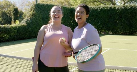 Smiling Friends Holding Tennis Equipment on Sunny Outdoor Court