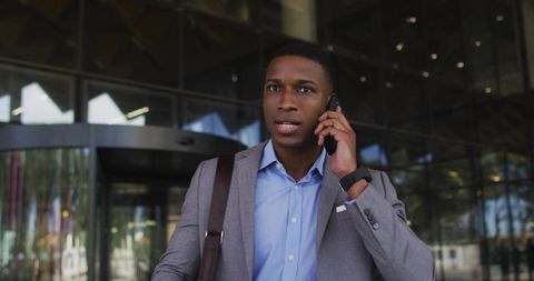 Businessman in Modern Suit Talking on Smartphone at Building Entrance