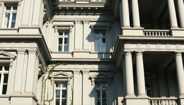 Sunlit classical stone facade with columns and sash windows on urban historic building