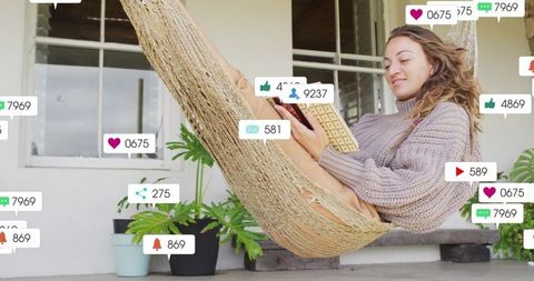 Woman relaxing in hammock on porch typing on tablet surrounded by social media notifications