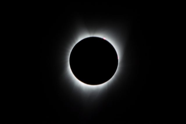 During the total solar eclipse, the Sun’s corona, only visible during the total eclipse, is shown as a crown of white flares from the surface. The red spots called Bailey's beads occurs where the moon grazes by the Sun and the rugged lunar limb topography allows beads of sunlight to shine through in some areas as photographed from NASA Armstrong’s Gulfstream III. Photo Credit: (NASA/Carla Thomas)
